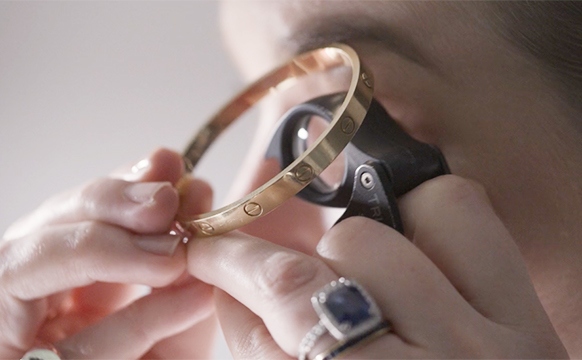 Cartier Love bracelet being examined with loupe to tell if it is real
