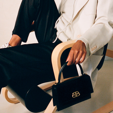 Image of woman with Balenciaga bag sitting in chair.