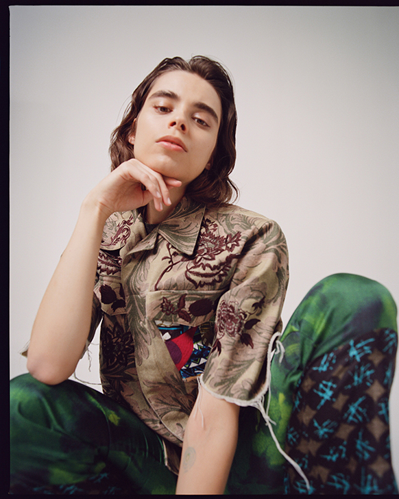Female model wearing Dries Van Noten printed top with upcycled patch details, and green printed pattern pants.