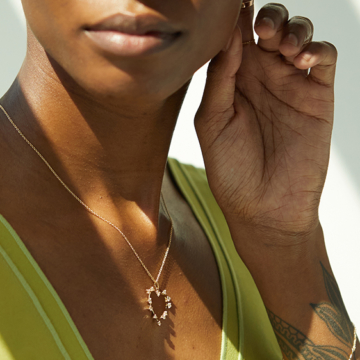 The RealReal x Catbird. Model wearing sustainable jewelry from upcycled collection next to logos