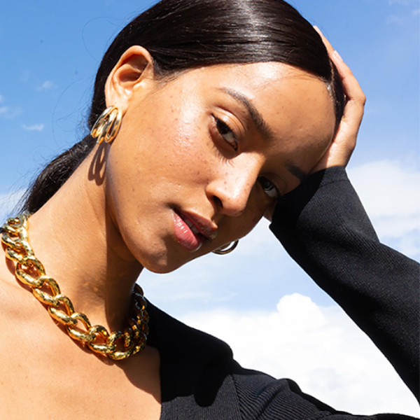 Shop. Sell. Dream. Model in gold necklace and hoop earrings and black sweetheart neckline top