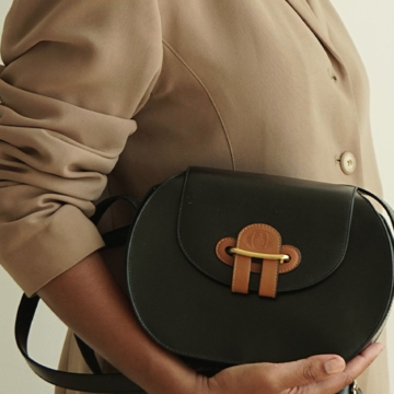 Model holding a brown, oval vintage Mark Cross handbag