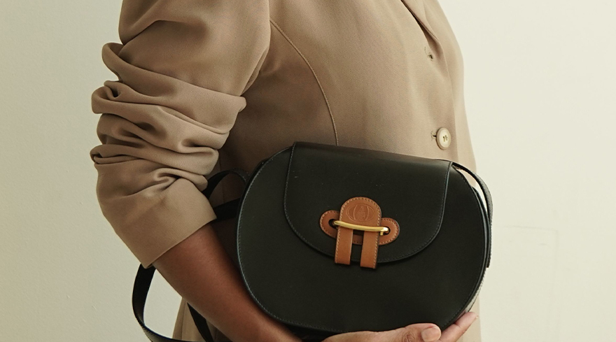 Model holding a brown, oval vintage Mark Cross handbag