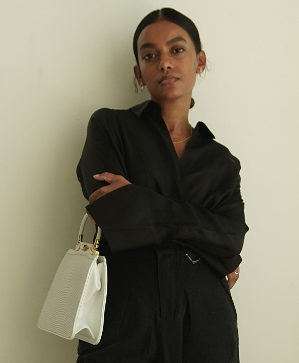 Stella Simona wearing a black blazer and vintage white Mark Cross handbag